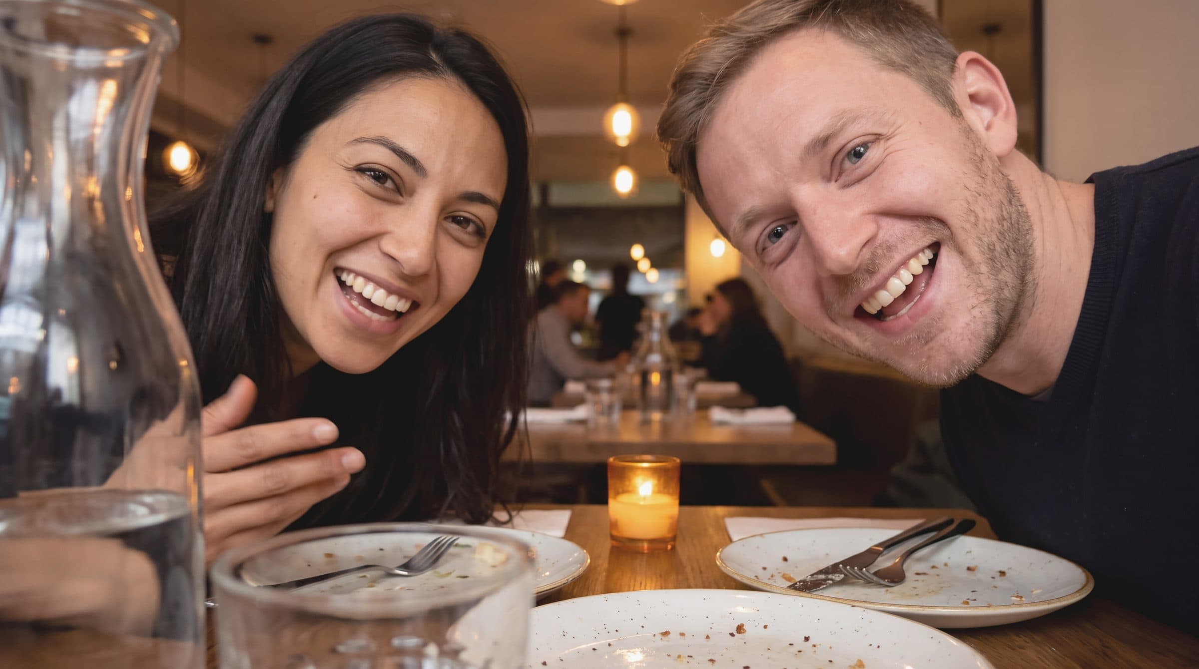 Two friends record a video review at their table after dinner